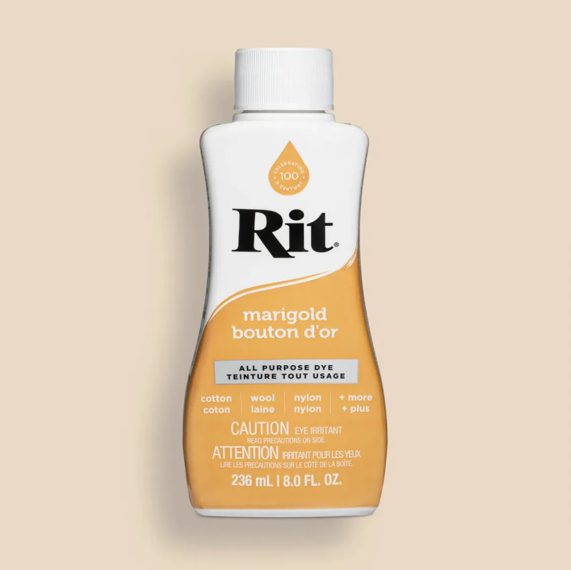 Bottle of Rit dye with marigold color on a beige background