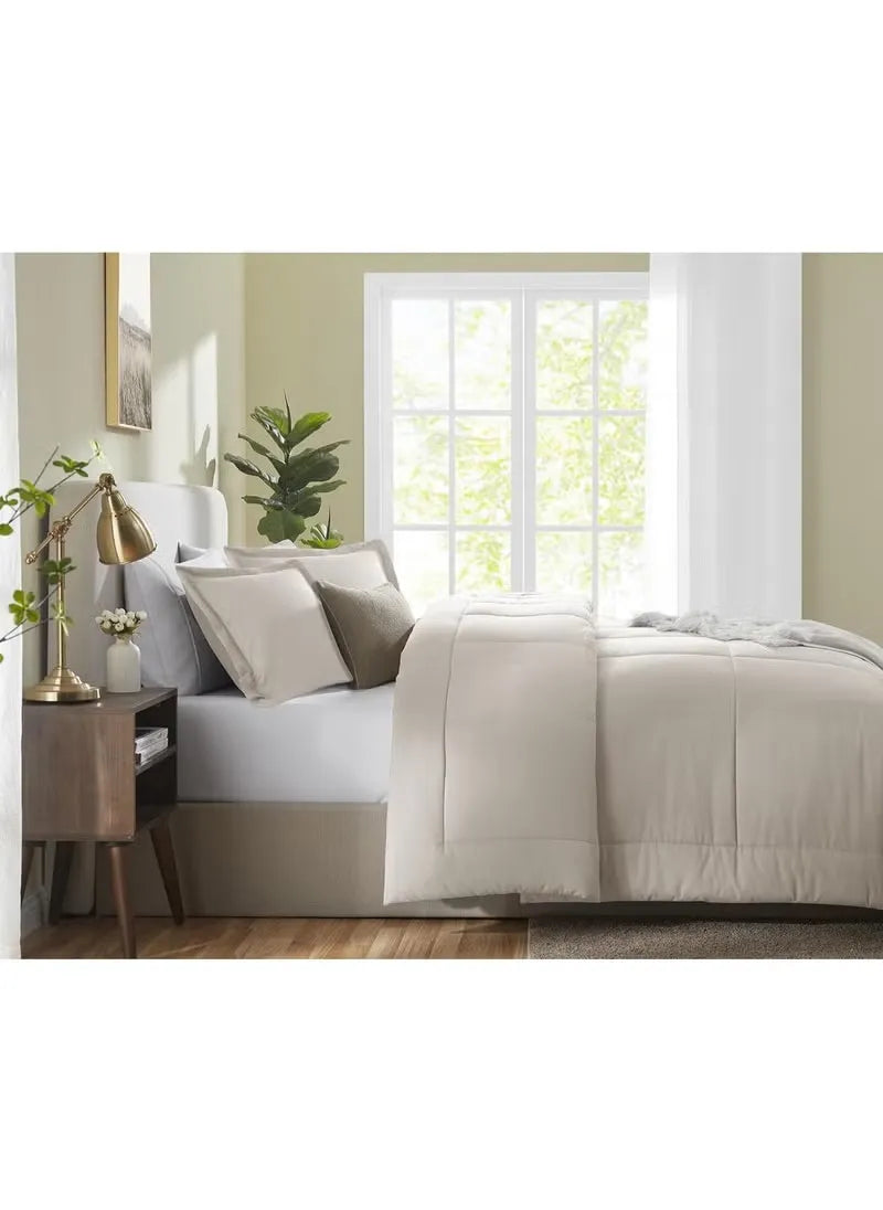 Neatly made bed with beige bedding in a bright bedroom