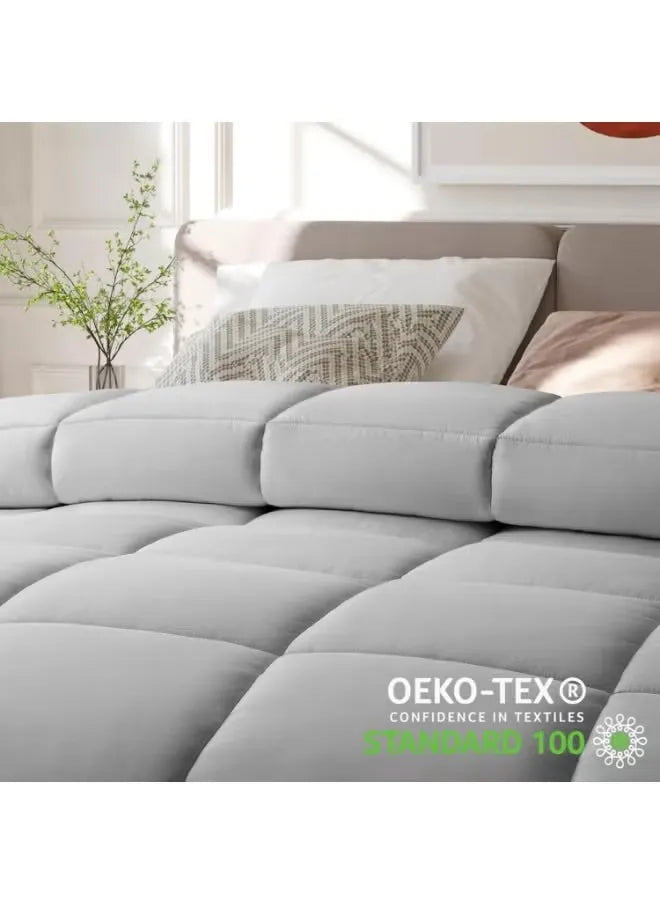 Gray quilted cover on a bed with pillows, featuring OEKO-TEX certification.