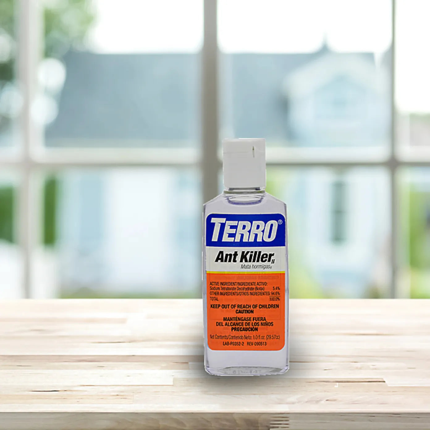 Bottle of Terro Ant Killer on a wooden surface with a blurred window background