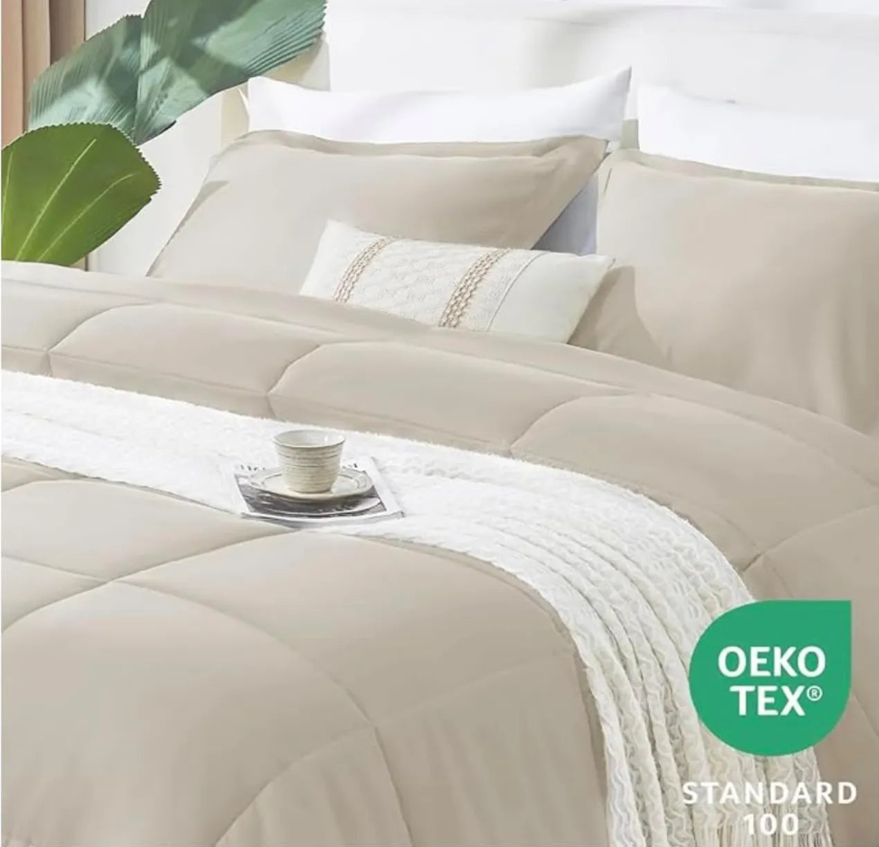 Beige bedding set on a bed with white pillows and a plant in the corner, featuring the OEKO-TEX Standard 100 logo.