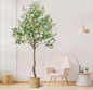 Artificial olive tree in a room with a chair and small table.